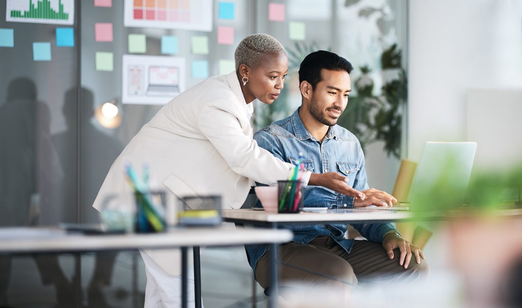 Woman and man discuss project on laptop in front of them.